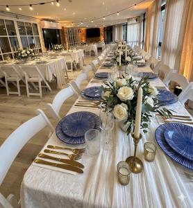 a long table with blue plates and flowers on it at Hotel Alma - Near The Sea in Netanya