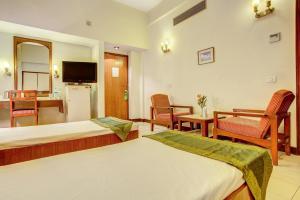 a hotel room with two beds and a dining room at Hotel Ajanta Continental in Dehradun +29 photos