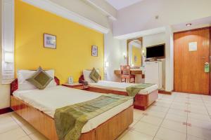 デヘラードゥーンにあるHotel Ajanta Continentalのベッド2台とテレビが備わるホテルルームです。