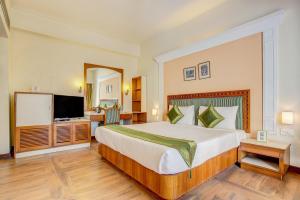 デヘラードゥーンにあるHotel Ajanta Continentalの大型ベッドとテレビが備わるホテルルームです。
