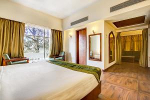 a bedroom with a large bed and a large window at Hotel Ajanta Continental in Dehradun