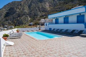 a swimming pool in front of a building with a mountain at Ancient Thera Apartments in Kamari