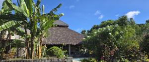 a resort building with a thatched roof and trees at Maison Carrée Andilana in Andilana