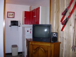 a tv sitting on top of a wooden table at STOP mon grand F2 face au parc des Écrins in Orcières +3 photos