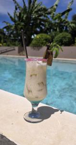 a drink sitting on a table next to a pool at Maison Carrée Andilana in Andilana