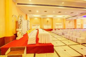 a banquet hall with white tables and white chairs at Hotel Ajanta Continental in Dehradun