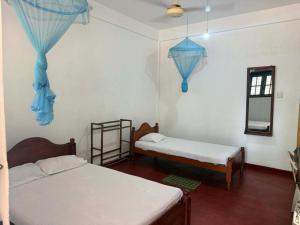 a room with two beds and blue drapes at Hasthi Resort in Polonnaruwa