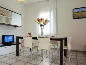 a dining room table with white chairs and a vase of flowers at Ville Verdi in Bibione