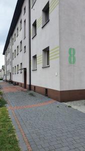 a large white building with a green cross painted on it at Apartament Ogrodzieniec in Ogrodzieniec