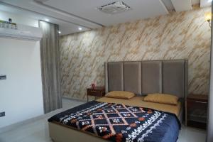 a bedroom with a bed with a padded headboard at Eifel Heights Apartments in Lahore
