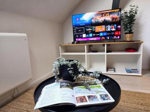 a table with a book and a tv in a room at Le cocon du Florival - Box à vélo - Guebwiller in Guebwiller