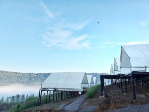 a group of buildings on top of a hill with fog at เขาเจ้าขา-เต็นท์กระโจมเขาค้อ in Khao Kho