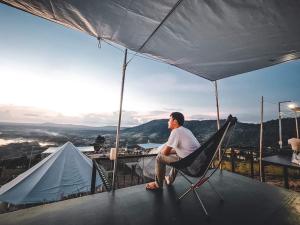 a man sitting in a chair on the edge of a tent at เขาเจ้าขา-เต็นท์กระโจมเขาค้อ in Khao Kho