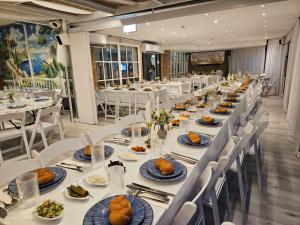 a long dining room with white tables and white chairs at Hotel Alma - Near The Sea in Netanya