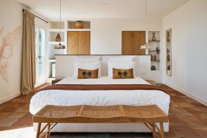 a bedroom with a large white bed with a wooden bench at Bastide Saint-Honorat in Grasse