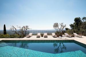 a swimming pool with lounge chairs and a view of the ocean at Bastide Saint-Honorat in Grasse