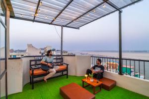 two men sitting on the balcony of a building at Madpackers Varanasi in Varanasi