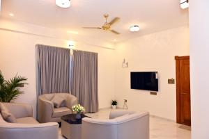 a living room with a ceiling fan and a tv at Selora Suites Serviced Apartments in Mysore +7 photos
