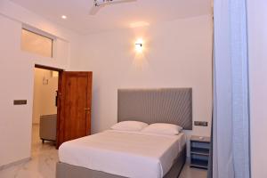 a white bedroom with a bed and a light at Selora Suites Serviced Apartments in Mysore