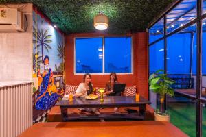 two women sitting at a table with a laptop at Madpackers Varanasi in Varanasi