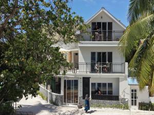 a white house with people sitting on the balcony at Alma Maldiva, Beach Hotel in Ariyaddu
