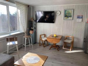 a living room with a table and chairs and a tv at Našio Kempingo Apartamentai in Antanaše