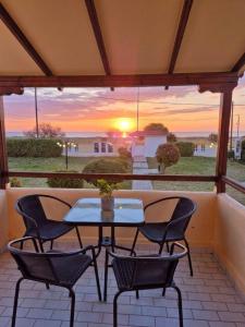 a patio with a table and chairs and a sunset at 5 Suites Αγιόκαμπος Αγιάς in Agiokampos