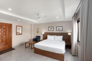 a bedroom with a white bed and a wooden door at Hotel Imphal by the Classic in Imphal