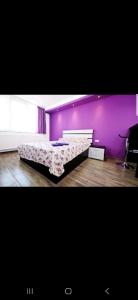 a bedroom with a bed with a purple wall at Tiglina in Galaţi