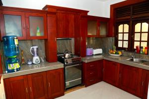 una cucina con mobili in legno rosso ed elettrodomestici in acciaio inossidabile di 4 S Villa a Tangalle