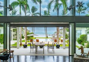 a room with a table and chairs and palm trees at Baan Asan in Taling Ngam Beach