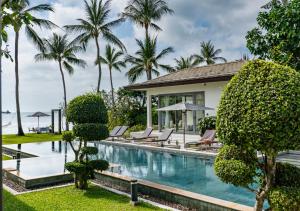 a swimming pool in front of a house with palm trees at Baan Asan in Taling Ngam Beach