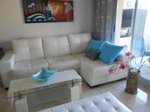 een woonkamer met een witte bank en blauwe kussens bij Jardinas de les Marinas in Denia