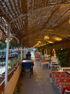 a covered patio with tables and chairs on the water at Al Baeirat Hotel in Luxor