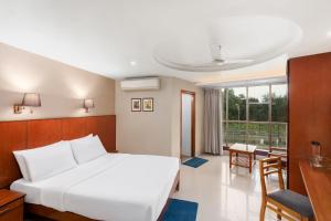 a bedroom with a white bed and a desk and a window at The Classic Hotel in Imphal