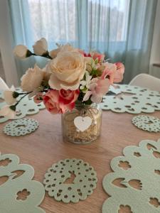 a vase filled with pink and white flowers on a table at Völgyzugoly Apartman in Kőszeg +2 photos