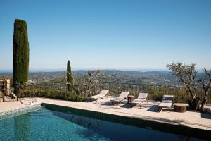a swimming pool with chairs and a view of the city at Bastide Saint-Honorat in Grasse