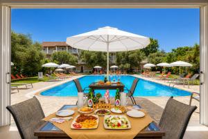 a table with food on it next to a pool at Kosmas Apartments in Roda