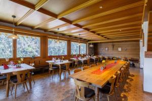ein Restaurant mit Holztischen und -stühlen und Fenstern in der Unterkunft Hotel Chavalatsch in Taufers im Münstertal