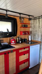 eine Küche mit roten und weißen Schränken und einer Spüle in der Unterkunft Tiny Haus Speyer in Langenselbold