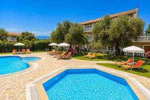 a pool at a hotel with chairs and umbrellas at Kosmas Apartments in Roda