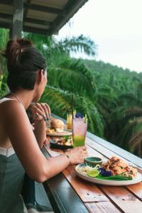 a woman sitting at a table with plates of food at KhaoSok Malin Glamping in Ban Bang Thong