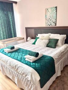 a large bed with green and white sheets and pillows at Lorena Holiday Spa Свети Спас in Velingrad +42 photos