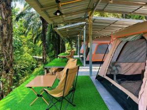 a patio with two tents and a table and chairs at KhaoSok Malin Glamping in Ban Bang Thong