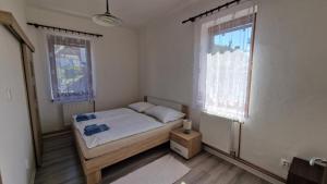 a small bedroom with a bed and two windows at Apartment LAURA in Žilina