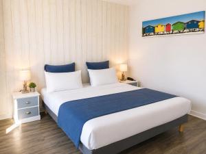 a bedroom with a large bed with blue and white sheets at Logis Latitude Ouest Hôtel Restaurant & Spa in Locronan