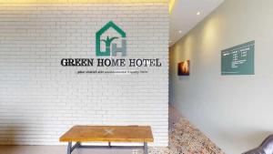 a green home hotel sign on a white brick wall at Hotel O Green Home Hotel in Sepang