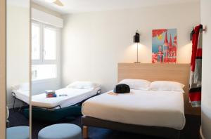 a hotel room with two beds and a mirror at The Originals Residence Appart'Hôtel Lauréades Clermont-Ferrand Centre Jaude in Clermont-Ferrand +40 photos