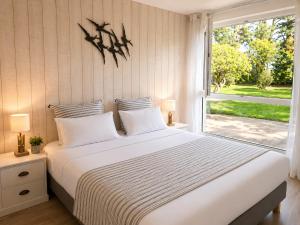 a bedroom with a large white bed with a window at Logis Latitude Ouest Hôtel Restaurant & Spa in Locronan