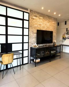 a living room with a television on a brick wall at סוויטת בית ינאי in Beit-Herut